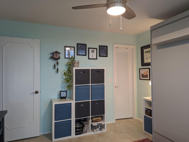 interior space featuring a textured ceiling, light tile patterned floors, and ceiling fan