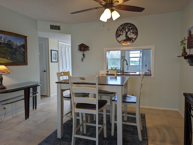 tiled dining space featuring sink, a textured ceiling, and ceiling fan