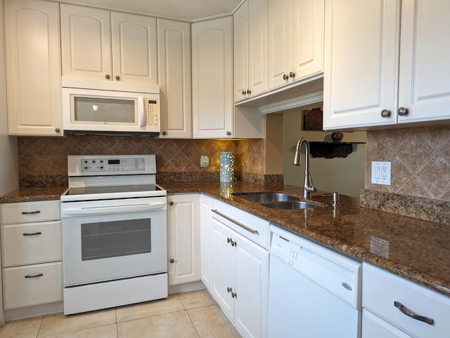 kitchen with dark stone countertops, white appliances, sink, and white cabinets