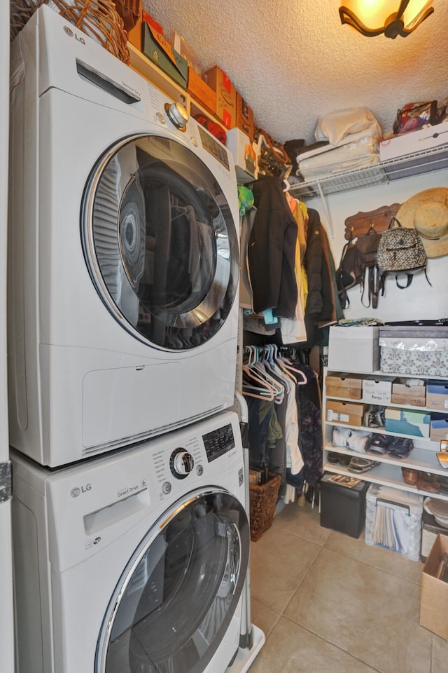 clothes washing area featuring stacked washer and clothes dryer, a textured ceiling, and light tile patterned floors