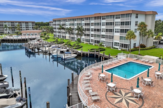 view of swimming pool featuring a yard, a water view, a boat dock, and a patio area