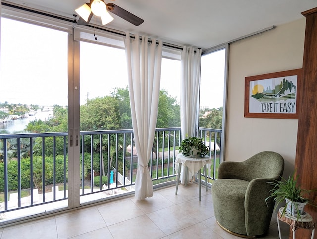 sunroom / solarium with ceiling fan and a water view