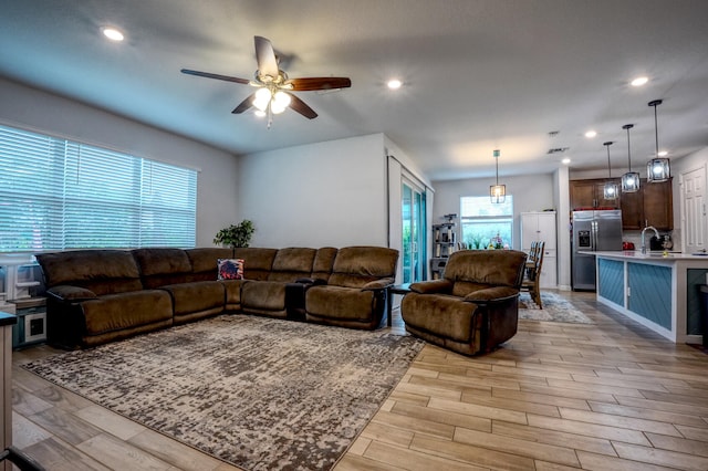 living room featuring ceiling fan, light wood-type flooring, and a wealth of natural light