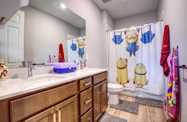 full bathroom with hardwood / wood-style flooring, vanity, shower / bath combo with shower curtain, and toilet