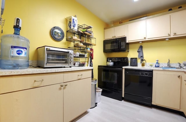 kitchen featuring black appliances, light hardwood / wood-style floors, and sink