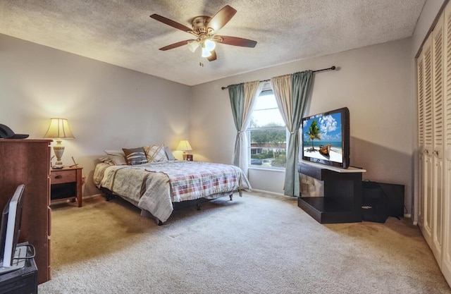 carpeted bedroom with ceiling fan, a closet, and a textured ceiling