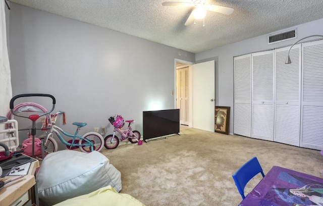 rec room with ceiling fan, light colored carpet, and a textured ceiling