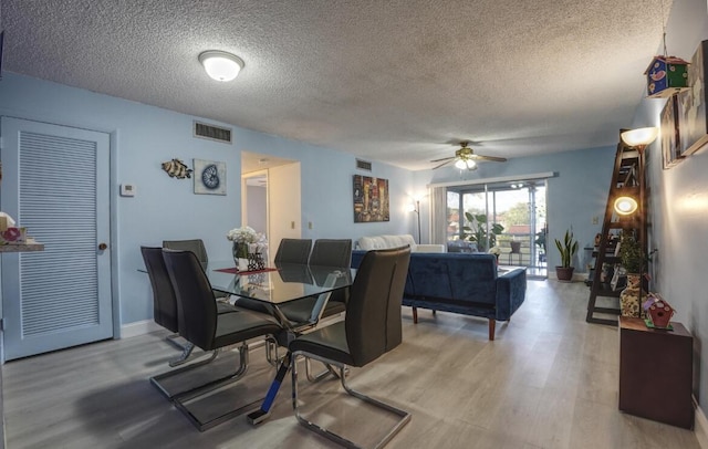 dining room featuring a textured ceiling, light hardwood / wood-style flooring, and ceiling fan