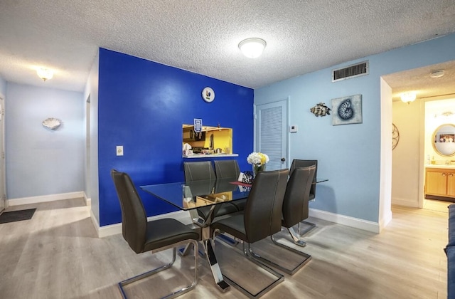 dining area featuring wood-type flooring and a textured ceiling