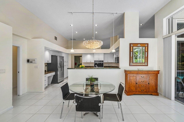 tiled dining space featuring a high ceiling, a notable chandelier, and a textured ceiling