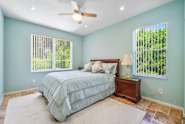 bedroom with ceiling fan, a textured ceiling, and multiple windows