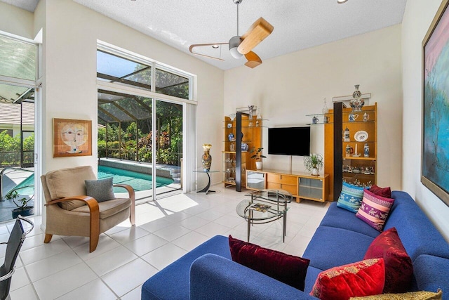 tiled living room with a towering ceiling, a textured ceiling, and ceiling fan