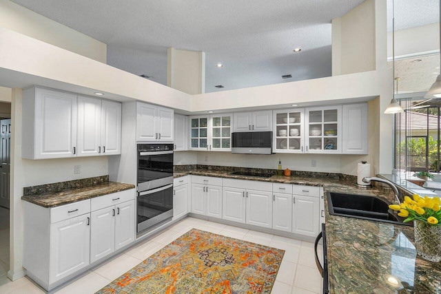 kitchen featuring appliances with stainless steel finishes, sink, a textured ceiling, a high ceiling, and white cabinets