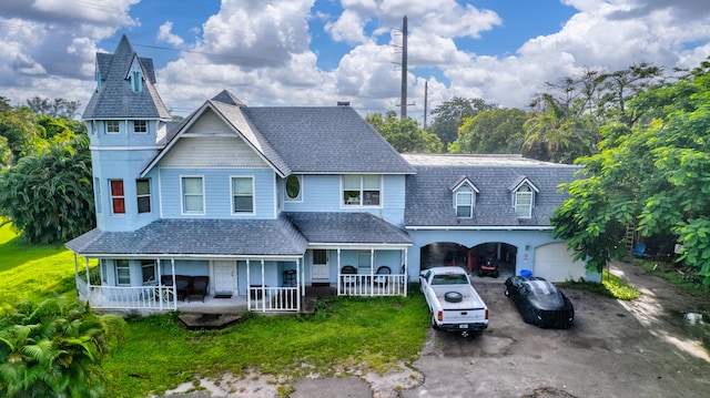 view of front of home with a front yard, a porch, and a garage