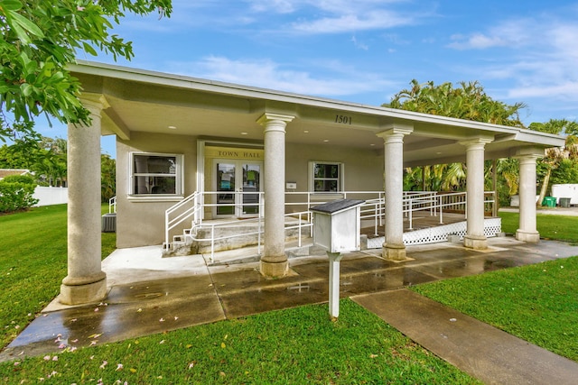 back of house featuring a lawn, covered porch, and central air condition unit