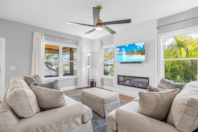 living room featuring ceiling fan, a fireplace, hardwood / wood-style floors, and a healthy amount of sunlight