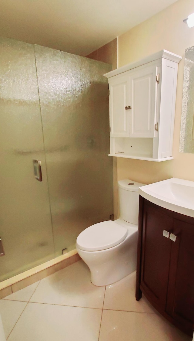 bathroom featuring vanity, toilet, tile patterned floors, and a shower with shower door