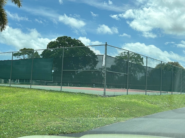 view of tennis court featuring a yard