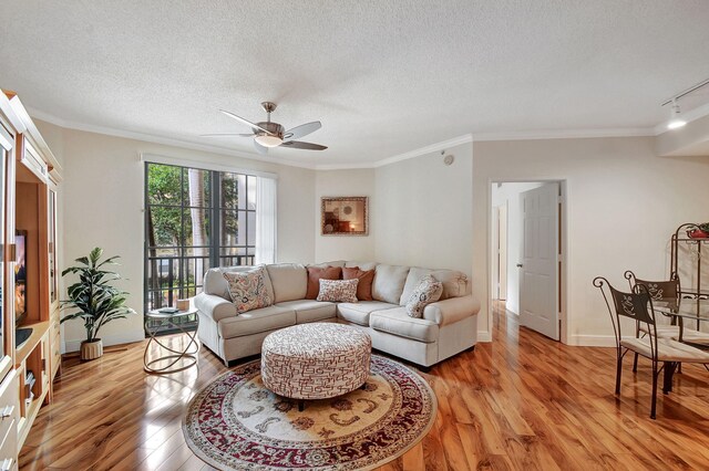 living room featuring a textured ceiling, light wood-type flooring, track lighting, ornamental molding, and ceiling fan