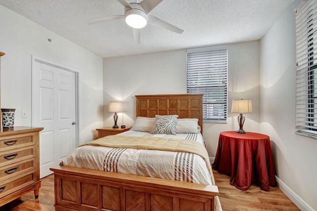 bedroom with light wood-type flooring, a textured ceiling, and ceiling fan