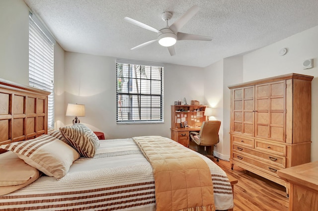 bedroom featuring a textured ceiling, light hardwood / wood-style floors, and ceiling fan