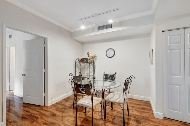 dining area featuring track lighting, hardwood / wood-style floors, and crown molding