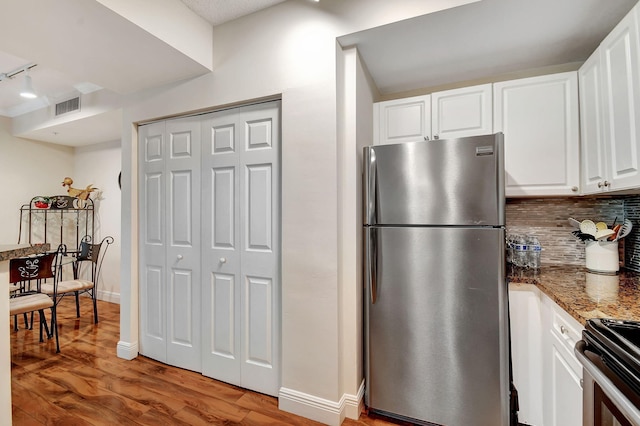 kitchen with dark stone counters, light hardwood / wood-style floors, track lighting, white cabinetry, and stainless steel appliances