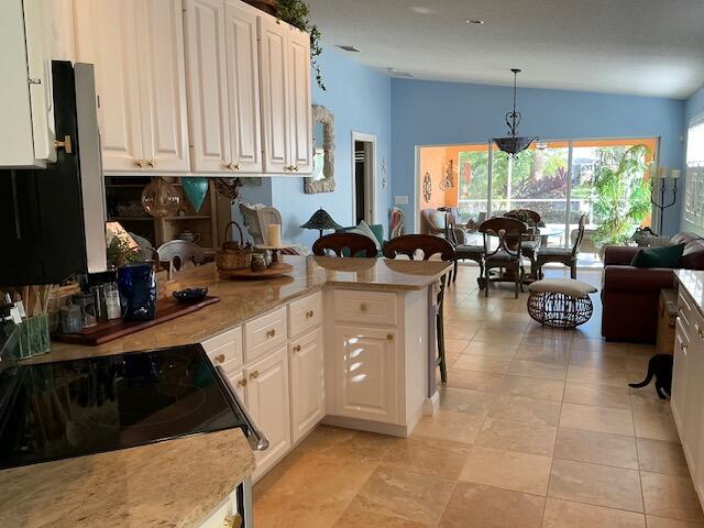 kitchen with white cabinets, kitchen peninsula, hanging light fixtures, and lofted ceiling