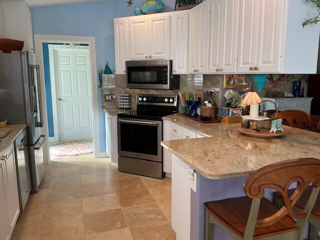 kitchen with stainless steel appliances, white cabinets, a breakfast bar, and tasteful backsplash