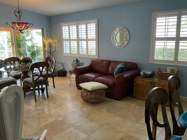 tiled living room featuring a wealth of natural light and a notable chandelier