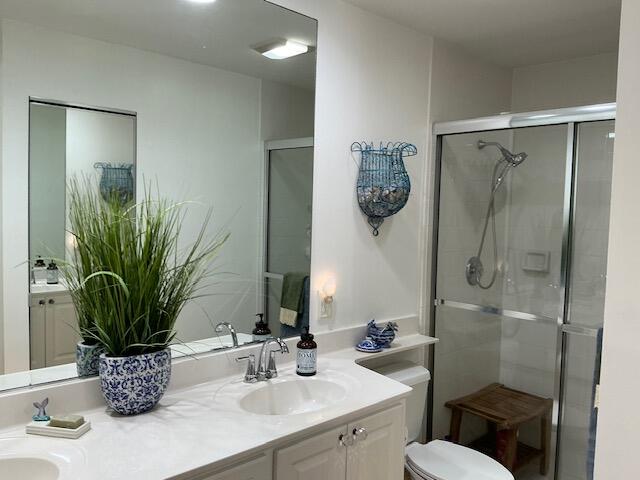 bathroom with a shower with shower door, vanity, and toilet