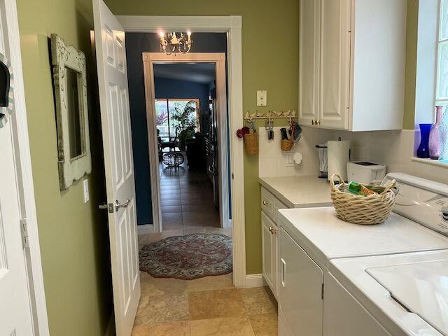 laundry room featuring cabinets, washer and dryer, and a notable chandelier