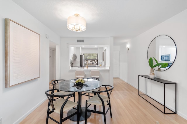 dining room featuring an inviting chandelier and light hardwood / wood-style flooring