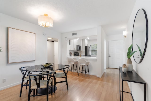 dining room featuring light wood-type flooring, a textured ceiling, and sink