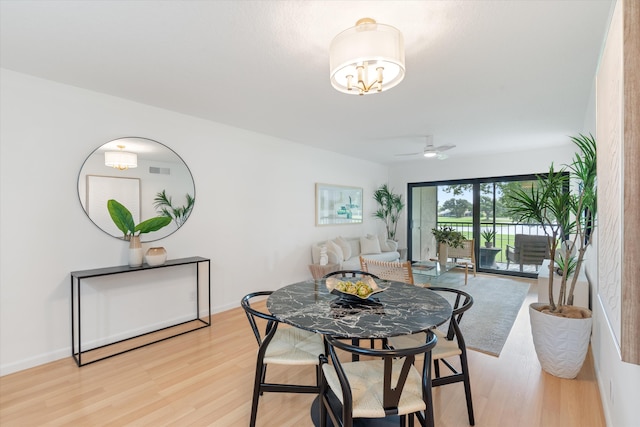 dining space featuring ceiling fan with notable chandelier and light wood-type flooring