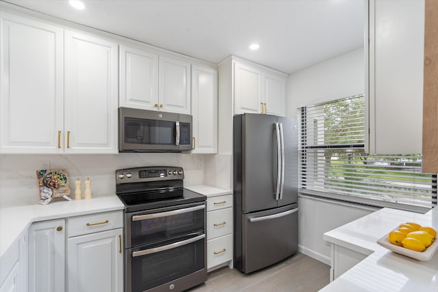 kitchen featuring white cabinets, appliances with stainless steel finishes, backsplash, and light hardwood / wood-style flooring