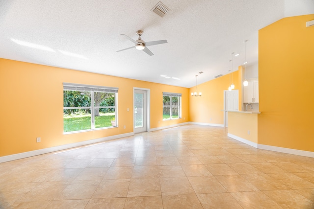 empty room featuring lofted ceiling, sink, light tile patterned floors, a textured ceiling, and ceiling fan with notable chandelier