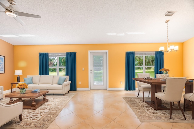 living room featuring a textured ceiling, a healthy amount of sunlight, and ceiling fan with notable chandelier