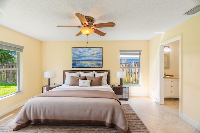 tiled bedroom with a textured ceiling, ensuite bath, and ceiling fan