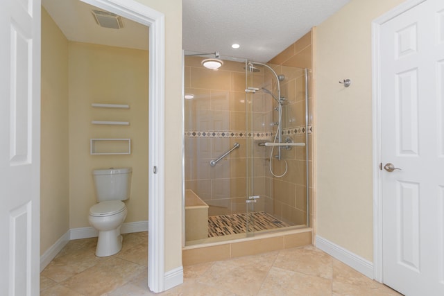 bathroom with a textured ceiling, a shower with door, tile patterned floors, and toilet