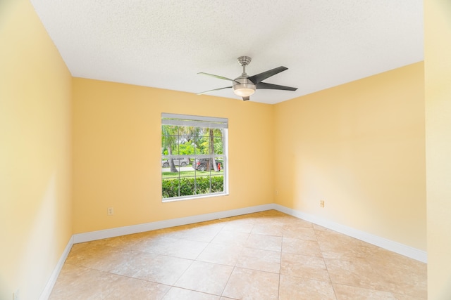 tiled empty room featuring ceiling fan and a textured ceiling