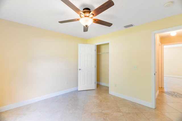 unfurnished bedroom featuring a closet, ceiling fan, light tile patterned floors, and a textured ceiling