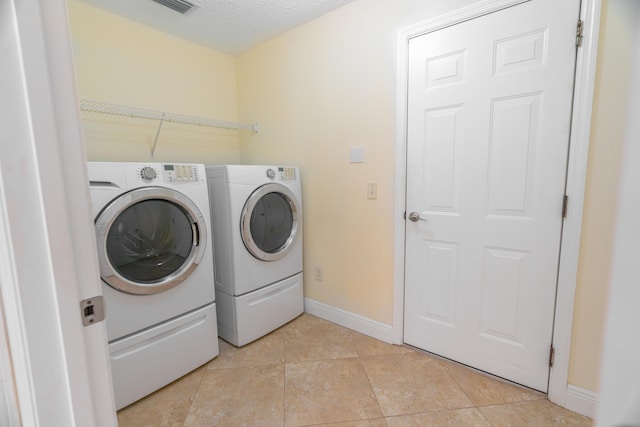 clothes washing area with light tile patterned floors, a textured ceiling, and independent washer and dryer