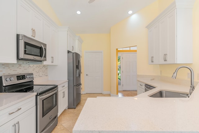 kitchen with light tile patterned floors, sink, tasteful backsplash, white cabinetry, and stainless steel appliances