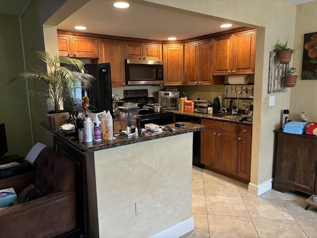 kitchen with black appliances, dark stone countertops, sink, and light tile patterned floors