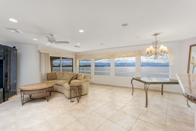 living room with light tile patterned floors, ceiling fan with notable chandelier, and a water view