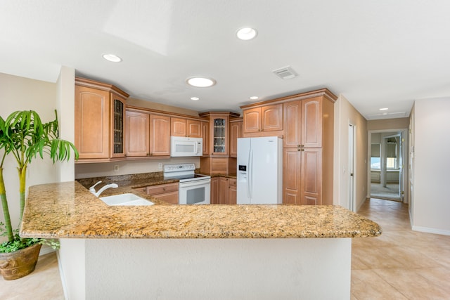 kitchen with kitchen peninsula, white appliances, light stone countertops, and sink