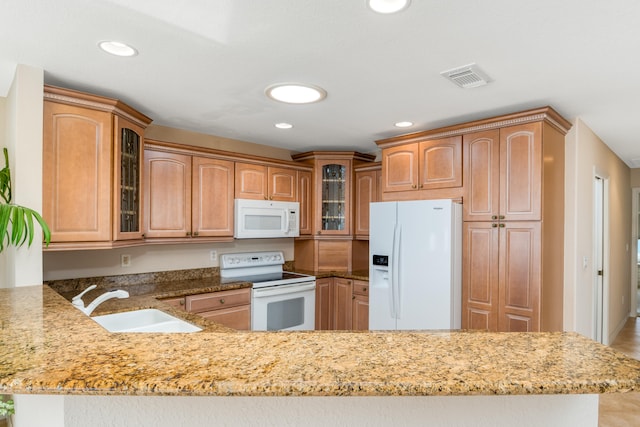 kitchen featuring kitchen peninsula, white appliances, light stone counters, and sink