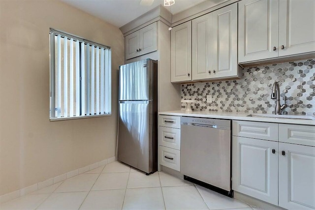 kitchen featuring light tile patterned floors, appliances with stainless steel finishes, sink, and decorative backsplash