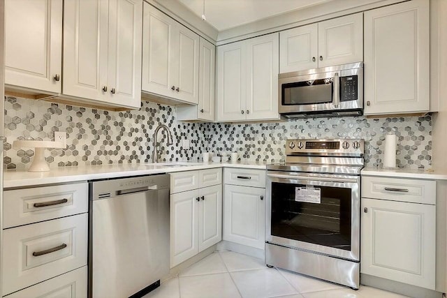 kitchen with appliances with stainless steel finishes, decorative backsplash, sink, and light tile patterned floors